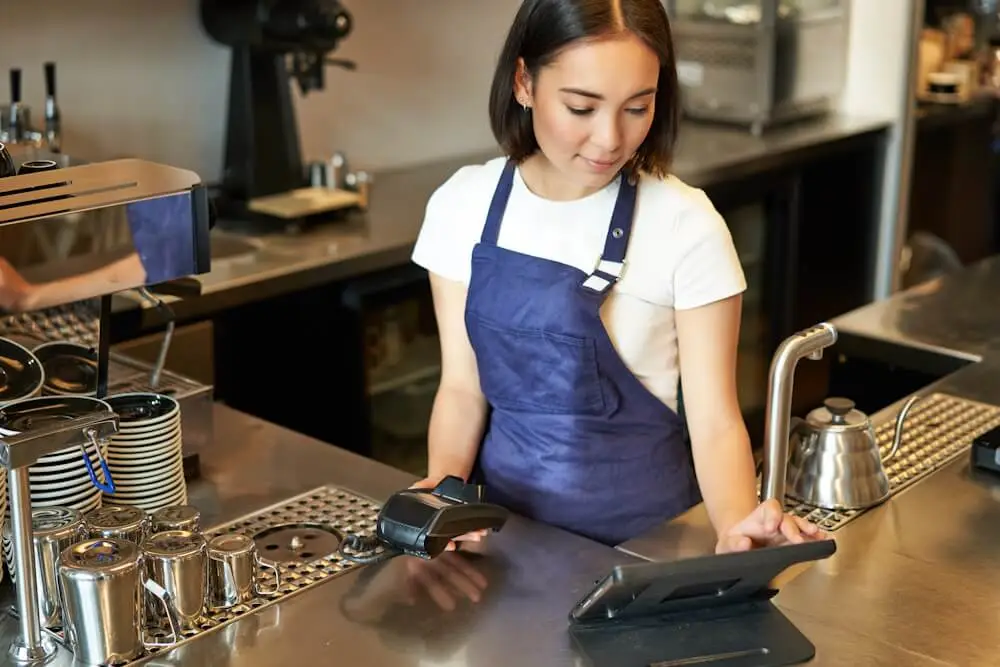 A customer tapping a card on a countertop payment terminal